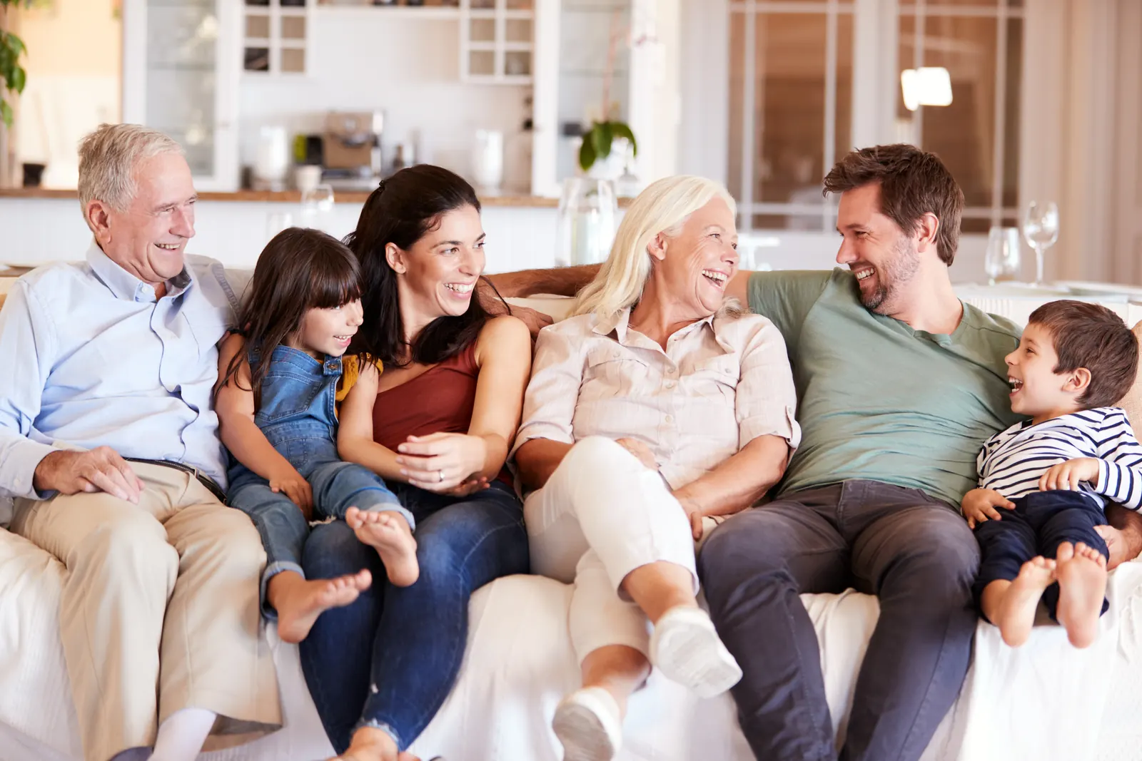 Drei Generationen einer Familie sitzen lachend zusammen auf dem Sofa